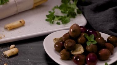 Taze pişmiş ev yapımı Grissini ekmek çubukları beyaz seramik tepside ve mutfak tezgahının üzerinde zeytinyağı ve fesleğen otu ile.