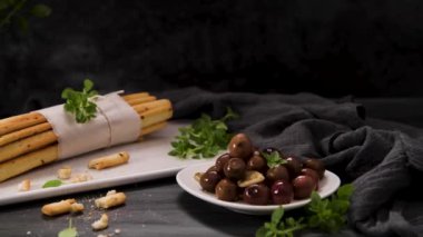 Taze pişmiş ev yapımı Grissini ekmek çubukları beyaz seramik tepside ve mutfak tezgahının üzerinde zeytinyağı ve fesleğen otu ile.