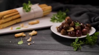Taze pişmiş ev yapımı Grissini ekmek çubukları beyaz seramik tepside ve mutfak tezgahının üzerinde zeytinyağı ve fesleğen otu ile.