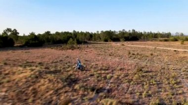Enduro motorsikletlerinden birinin patikadan geçerken ya da çam ağaçlarının bulunduğu alanda kırsal alandaki yol eğitiminde çekilmiş hava aracı görüntüsü. Adrenalin yoğunluğu eğlencesi.