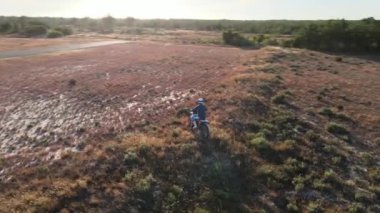 Enduro motorsikletlerinden birinin patikadan geçerken ya da çam ağaçlarının bulunduğu alanda kırsal alandaki yol eğitiminde çekilmiş hava aracı görüntüsü. Adrenalin yoğunluğu eğlencesi.