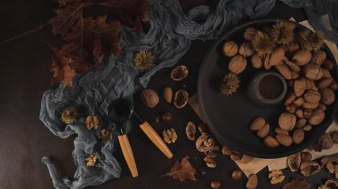 Fındıkkıran aleti ve siyah seramik tabağıyla sonbahar kuru meyveleri masada..