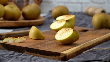 Yarı kesilmiş bir elma ve tarçınla hafifçe tozlanmış küçük bir kama, kırsal bir tahta kesme tahtasının üzerinde dinleniyor. Sahne bir bıçak, sicim ve bir kase tarçınla hazırlandı. Bu da lezzetli bir atıştırmalık için samimi ve sonbahar hazırlıklarını gösteriyor..