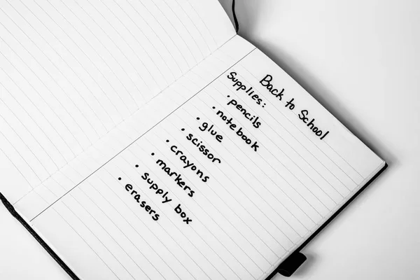 Handwritten shopping list of back to school supplies written on page of a notebook