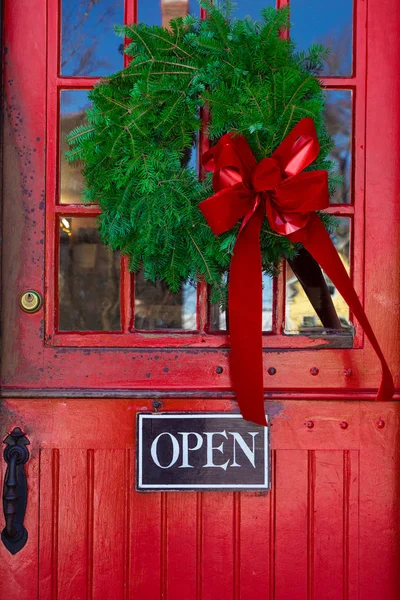 Red Store entrance door with open sign and Christmas wreath