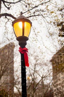 Madison Square Park, New York City Manhattan'dan görülen arka planda Flatiron Binası ile Noel için sokak lâmbası direği kırmızı yay ile dekore edilmiş