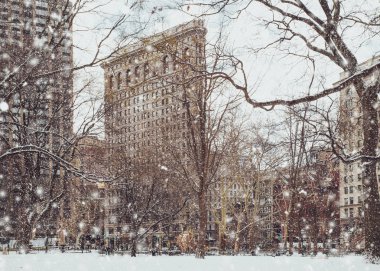 Kış kar fırtınası sırasında düşen kar taneleri ile Manhattan New York City şehir merkezinin içinde Madison Square Park tarihi Flatiron Binası görünümünü