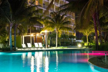 Güzel resort hotel havuz ışıkları ve tropikal konumda palmiye ağaçları ile gece