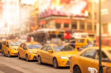 Güneş ışığı ile Manhattan şehir merkezinin içinde acele saatte New York'ta sarı taksi taksi bir satırının ufuk bulanıklık