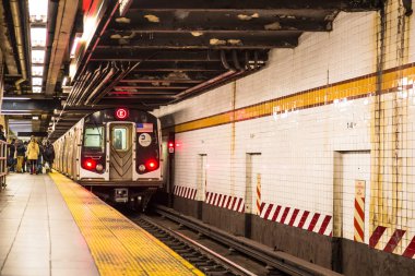 New York City - 3 Aralık 2016: Tren yaklaşırken ve insanlar görünürken metronun yeraltı New York metrosunun içinden görünümü.
