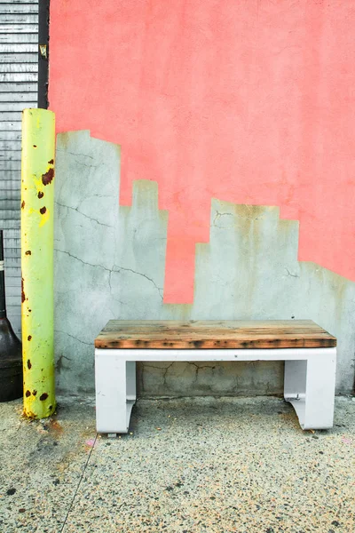 カラフルに塗られたセメントのひび割れた壁に対する歩道上のベンチ — ストック写真