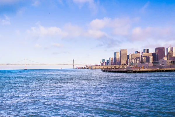 City of San Francisco California seen from the Bay with Bay Bridge, docks and buildings of skyline in view.