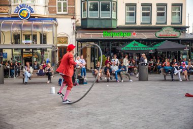 AMSTERDAM, NETHERLANDS - SEPTEMBER 1, 2018: Street performer entertains crowd on urban street in the city of Amsterdam. clipart