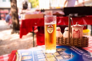 COLOGNE, GERMANY - SEPTEMBER 4, 2018:  Traditional glass of Kolsch beer seen in outdoor restaurant in Cologne Germany clipart