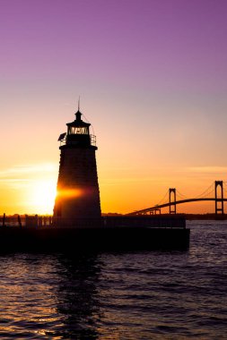 Sunset over Newport Harbor Lighthouse with bridge and colorful sky clipart