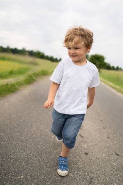 Küçük çocuk kırsal yolda oynuyor ve yürüyor.