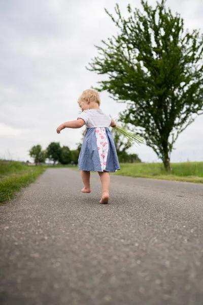 Kleines Mädchen läuft auf Landstraße — Stockfoto