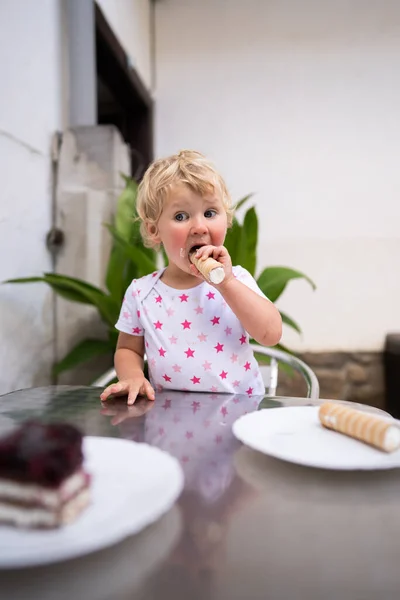 Bambina mangiando tubo con panna montata — Foto Stock