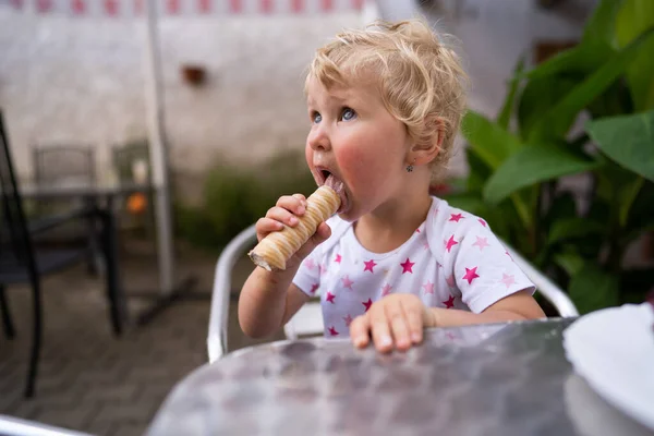 Bambina mangiando tubo con panna montata — Foto Stock