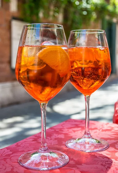 A glass with bright orange liquid, ice and a slice of orange, Sp — Stock Photo, Image