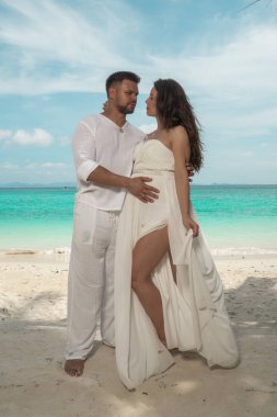 Çekici genç bir tropik adada kaç. Güzel kadın ve erkek birbirlerine kucaklayan ve trpoical tatil tatil kaçamağı zevk beyaz elbise giyen