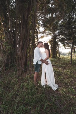 Çekici romantik genç kaç gün batımı sırasında tropikal bahçe içinde
