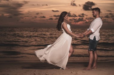 Güzel gün batımı sırasında tropikal kum plajındaki çekici romantik genç Çift