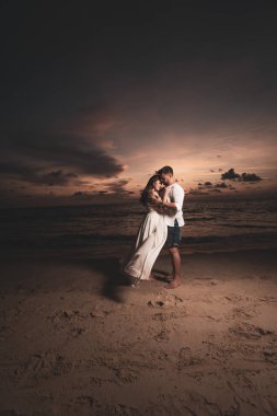 Güzel gün batımı sırasında tropikal kum plajındaki çekici romantik genç Çift