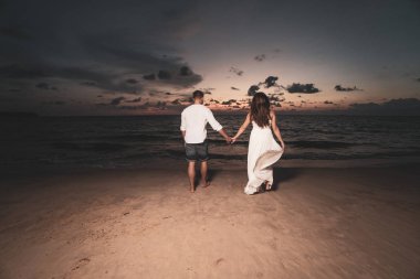 Güzel gün batımı sırasında tropikal kum plajındaki çekici romantik genç Çift