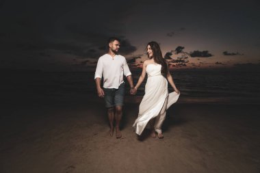 Güzel gün batımı sırasında tropikal kum plajındaki çekici romantik genç Çift