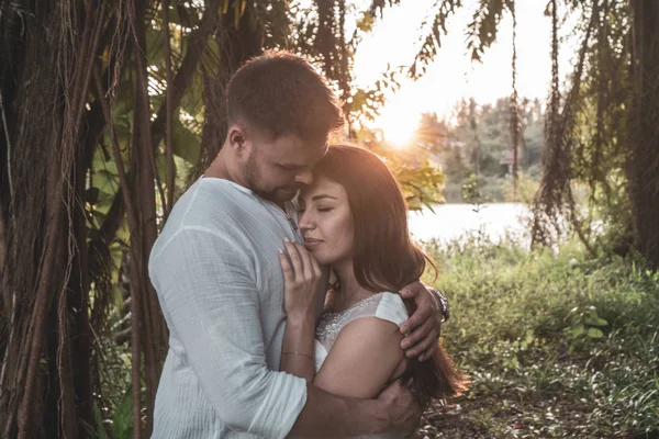 迷人的浪漫年轻夫妇在热带花园在日落期间 — 图库照片