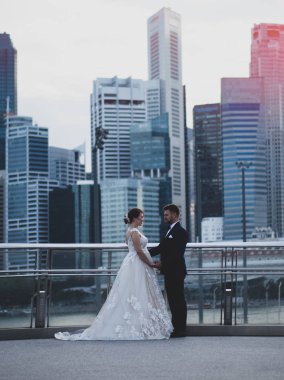 Çekici genç ve zarif bir çift birbirine üzerinde güzel Singapur Nehri ve cityscape arka plan ayakta bakarak