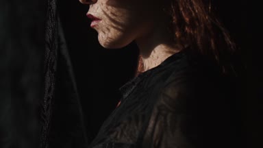 Güzel kadının dikey, dantel desen gölge ve güneş ışığı yüzünde / güzel kadın pencereden bakarak onun yüzünde - ağır çekimde video dantel perde modeli gölge ve güneş ışınları var.