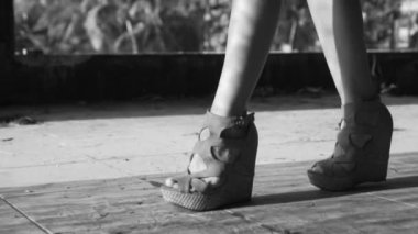 Tatlı kadının bacak yürüme / Closeup kadının bacak yürüme takozlar giyiyor. Kız onu bacaklar - siyah ve beyaz video ağır çekimde gölge ve güneş ışınları ile platform sandaletler içinde