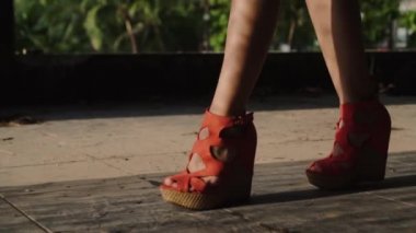 Tatlı kadının bacak yürüme / portre kadının bacakları kırmızı takozlar yürüyüş giyiyor. Kız bacaklarını - ağır çekimde video gölge ve güneş ışınları ile platform sandaletler içinde