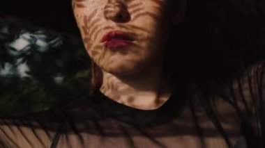 Güzel kadının dikey, dantel desen gölge ve güneş ışığı yüzünde / güzel dantel kumaş ile oynayan kadın. O pencerenin yakın duran ve dantel desen gölge ve güneş ışınlarının yüzünde - ağır çekimde video var