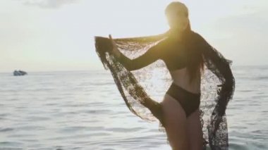 Siyah mayo onu tatil sahilde günbatımı sırasında zevk günbatımı / güzel kadında sırasında dantel eşarp ile oynarken sahilde güzel bir kadın. Kaygısız kadın siyah dantel kumaş - ağır çekimde video ile döşeme