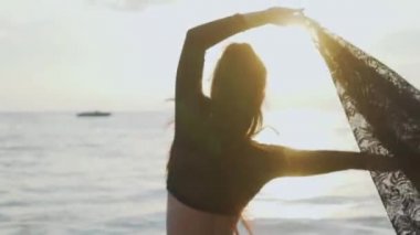 Siyah mayo onu tatil sahilde günbatımı sırasında zevk günbatımı / güzel kadında sırasında dantel eşarp ile oynarken sahilde güzel bir kadın. Kaygısız kadın siyah dantel kumaş - ağır çekimde video ile döşeme