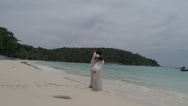 迷人的年轻夫妇在热带岛屿 鸟瞰的迷人的年轻夫妇在热带岛屿 美丽的女人和男人穿着白色的衣服拥抱对方 享受热带假期假期度假 — 图库视频影像