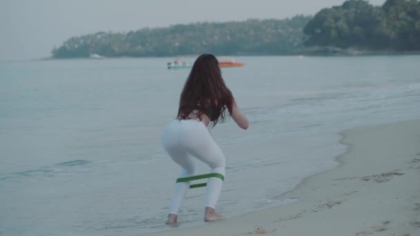 美丽的女孩在沙滩上锻炼 美丽的年轻女孩在沙滩上的早晨锻炼的鸟瞰图 — 图库视频影像