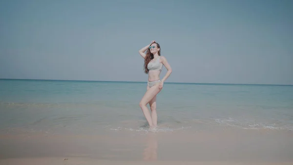 ビキニや空の背景の上の夏の休暇中に熱帯のビーチでリラックスしたサングラスで美しい少女 — ストック写真