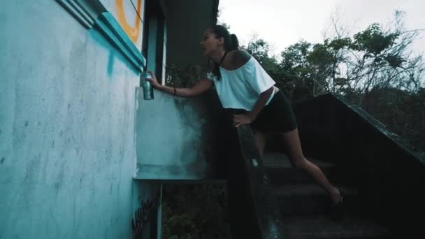 Graffiti művész lány/Graffiti művész lány festés c elhagyott épület falán. Aeroszol spray palackot permetezés színes festék szép nő. Városi szabadban művészeti koncepció