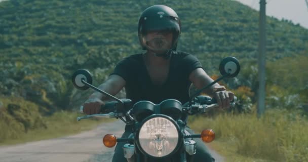 免费摩托车车手 前景色凉爽的旅客驾驶他的菜刀摩托车在热带岛屿公路与美丽的山景观在多云清晨 视频慢动作 — 图库视频影像