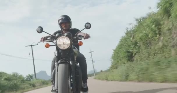 熱帯の島の道の彼のチョッパー バイクを運転中曇り早朝クールな旅行者の無料バイク ライダー フロント ビュー — ストック動画