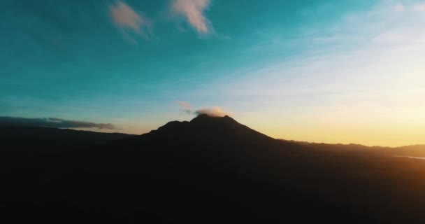 バトゥール火山シルエット 空中と明るい日の出の空中パノラマ ビューは インドネシア バリ島で美しい日の出の間バトゥール火山のビューをドローンします — ストック動画