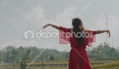 Güzel kadını pirinç tarla / arkadan görünüşü güzel genç kadın kırmızı şeffaf elbiseli pirinç alan - ağır çekimde video boyunca yürüyüş