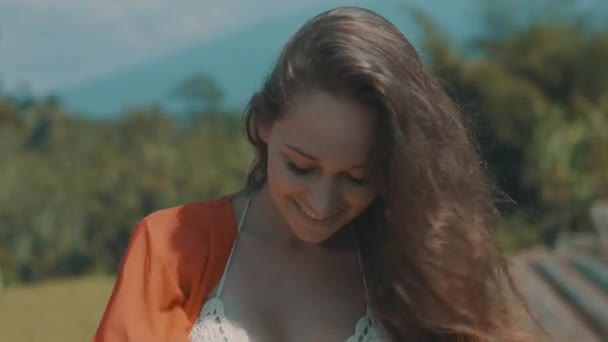 美しい田んぼで女性の肖像 赤いドレスの美しい若い女性のポートレート クローズ アップ カメラにスローモーションのビデオを見ながら笑みを浮かべて — ストック動画