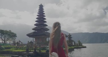 Genç kadın turist arkadan görünüm üzerinde Adası Bali, Endonezya - video ağır çekimde Ulun Danu Batur tapınağında onu tatil sahiptir