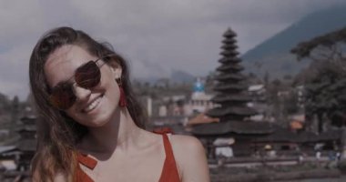 Portre portre genç kadın turist üzerinde Adası Bali, Endonezya - video ağır çekimde Ulun Danu Batur tapınağında onu tatil sahiptir