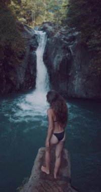 Genç güzel turistik Bali Adası Aling-Aling Şelalesi ziyaret / arkadan görünüm genç güzel turistik Bali Adası, Endonezya - ağır çekimde dikey video Aling-Aling Şelalesi ziyaret